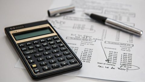 A calculator next to a sheet delineating investments and ROI on investments.