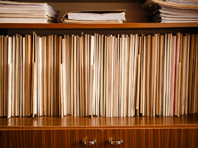 A bunch of manilla folders vertically arranged within a wooden credenza.