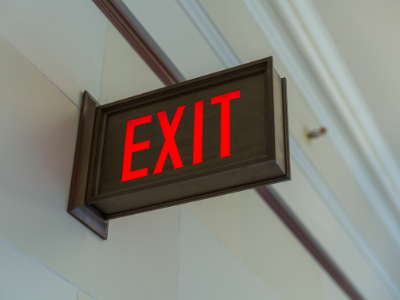 A black EXIT sign mounted on a white wall.