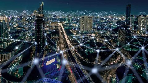 A city view at night with lines of light flowing through it depicting information traveling.