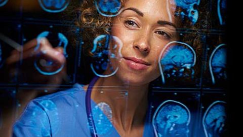 A female medical professional studying brain scan images.